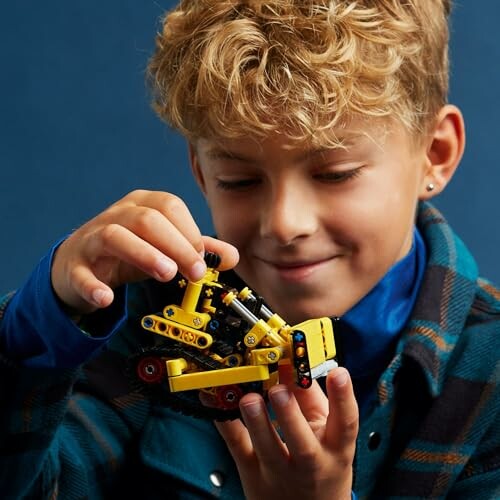 Child playing with a yellow Lego toy construction vehicle.