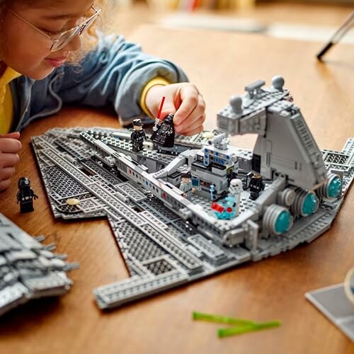 Child assembling a LEGO starship on a table.