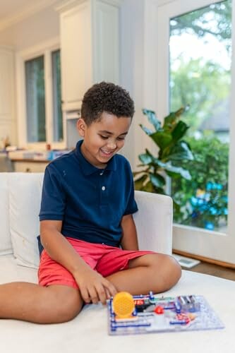 Child playing with an electronic toy on a couch.