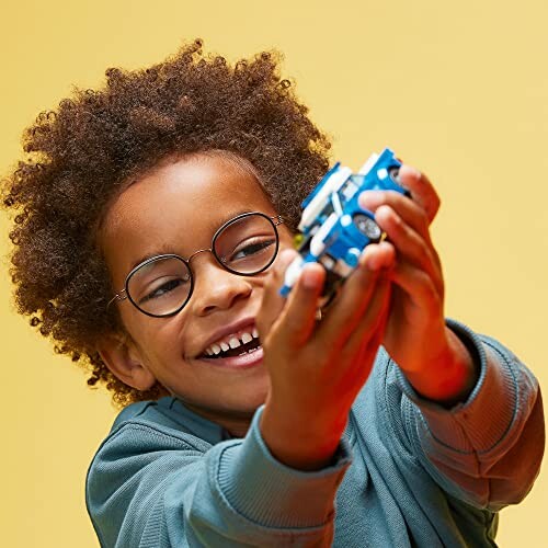 Child with glasses playing with a blue toy.