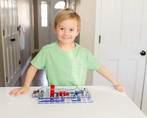 Child smiling while playing with an electronic circuit kit on a table.