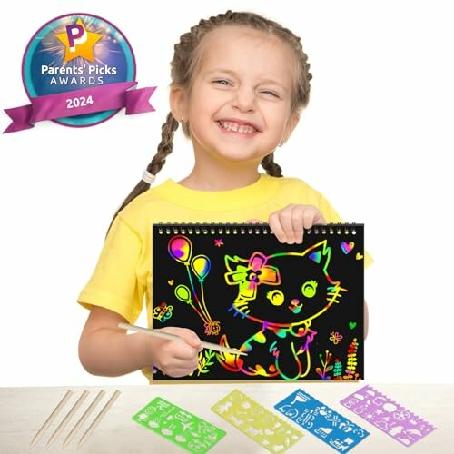 Smiling child holding a colorful scratch art drawing with stencils and tools.