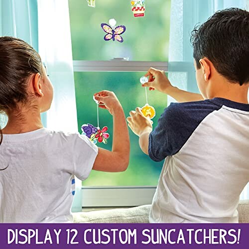 Two children hanging colorful suncatchers on a window.