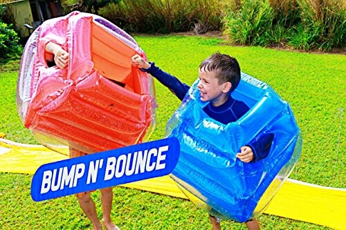 Children playing with inflatable bumper toys in a backyard.