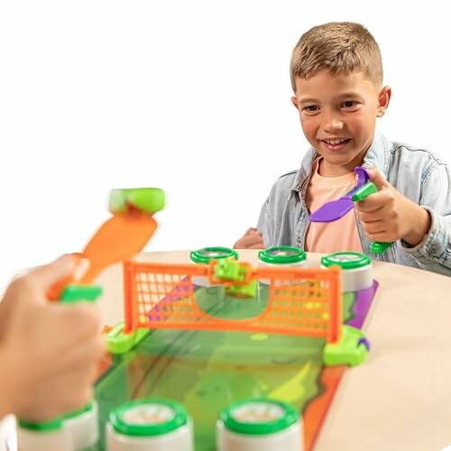 Children playing table hockey game with paddles and goal.