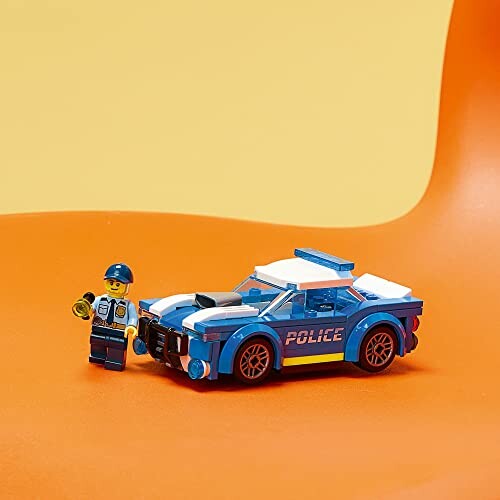 Lego police car with a Lego police figure on an orange surface.