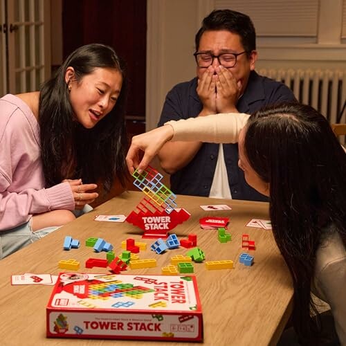 Three people playing a tower stacking board game at a table.